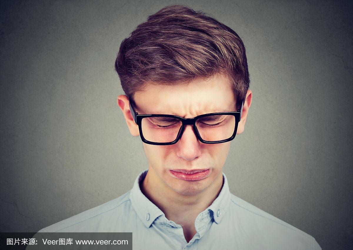 一个戴着眼镜哭泣的少年男子的特写