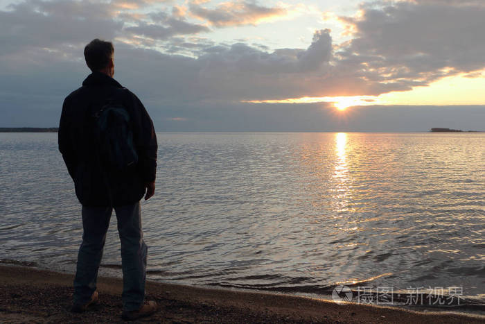 男人站在河岸边在日落