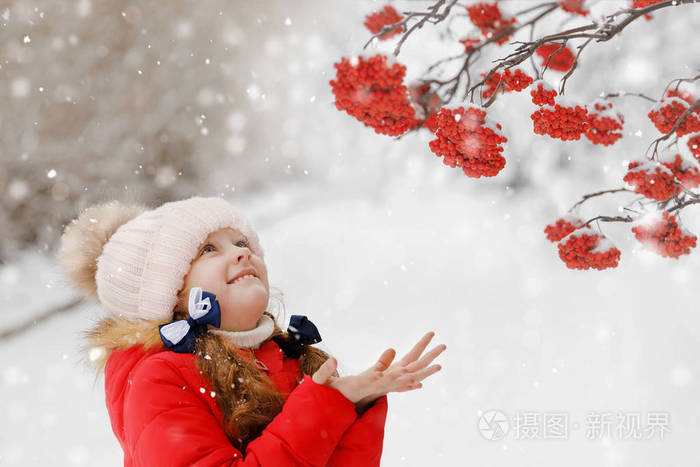 可爱的小女孩她伸手去抓飘落的雪花