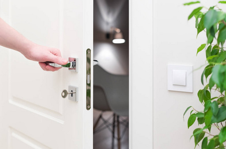 铬密钥打开门.现代白门镀铬金属手柄和男子的手臂照片