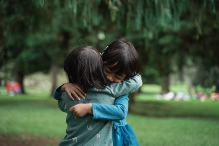 拥抱的可爱亚洲姐妹小女孩拥抱着彼此的朋友照片