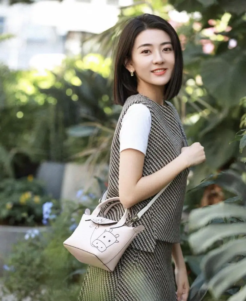 梁洁的手上则是提着一只淡粉色的小牛包包,俏皮又可爱,整个造型简单又