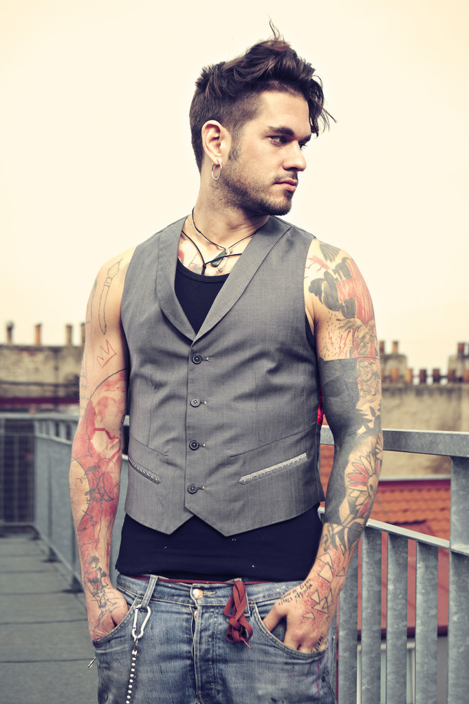 年轻的纹身男模特,年轻人纹身男模特在时装城外景拍摄期间摆姿势.