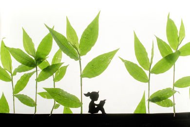 树叶中坐着读书的小女孩剪影