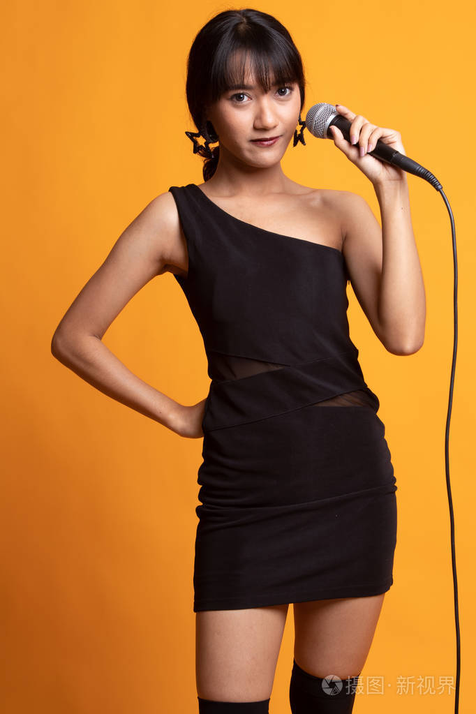 年轻美丽的亚洲女歌手用麦克风唱歌