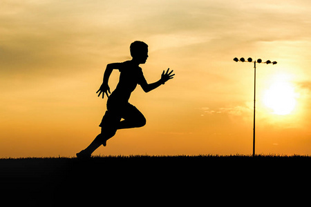 奔跑田一个运动男孩在北爱达荷州的日落田野上奔跑.照片