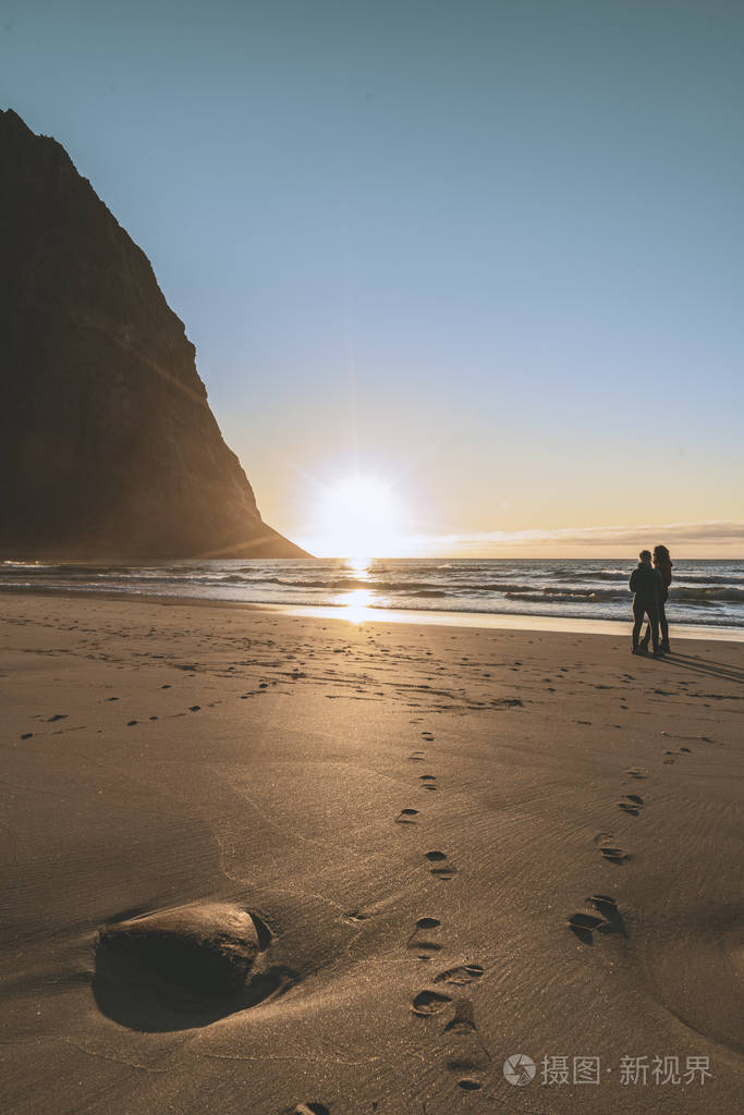 落日后的山上的海滩挪威一对情侣在海滩上拥抱